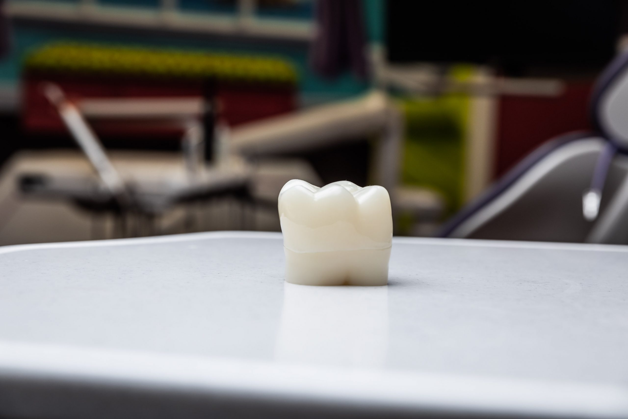 A close-up image of a 3D model of a white tooth on a metal tray. 