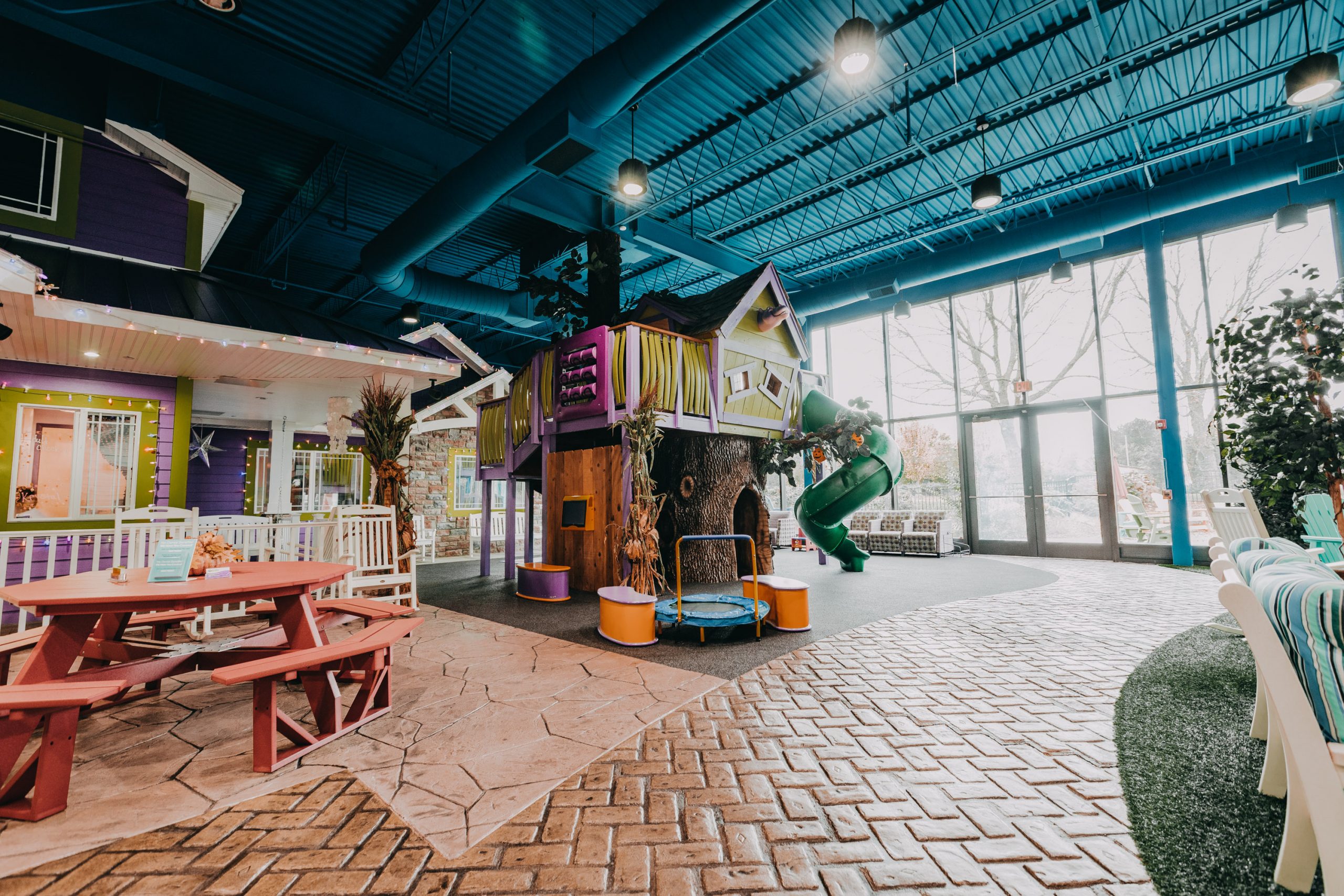 Newtown Dentistry dental home with indoor treehouse and slide with red picnic benches and brick floor.