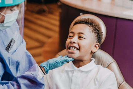 An orthodontist examines a young boy’s smile during an orthodontic evaluation.
