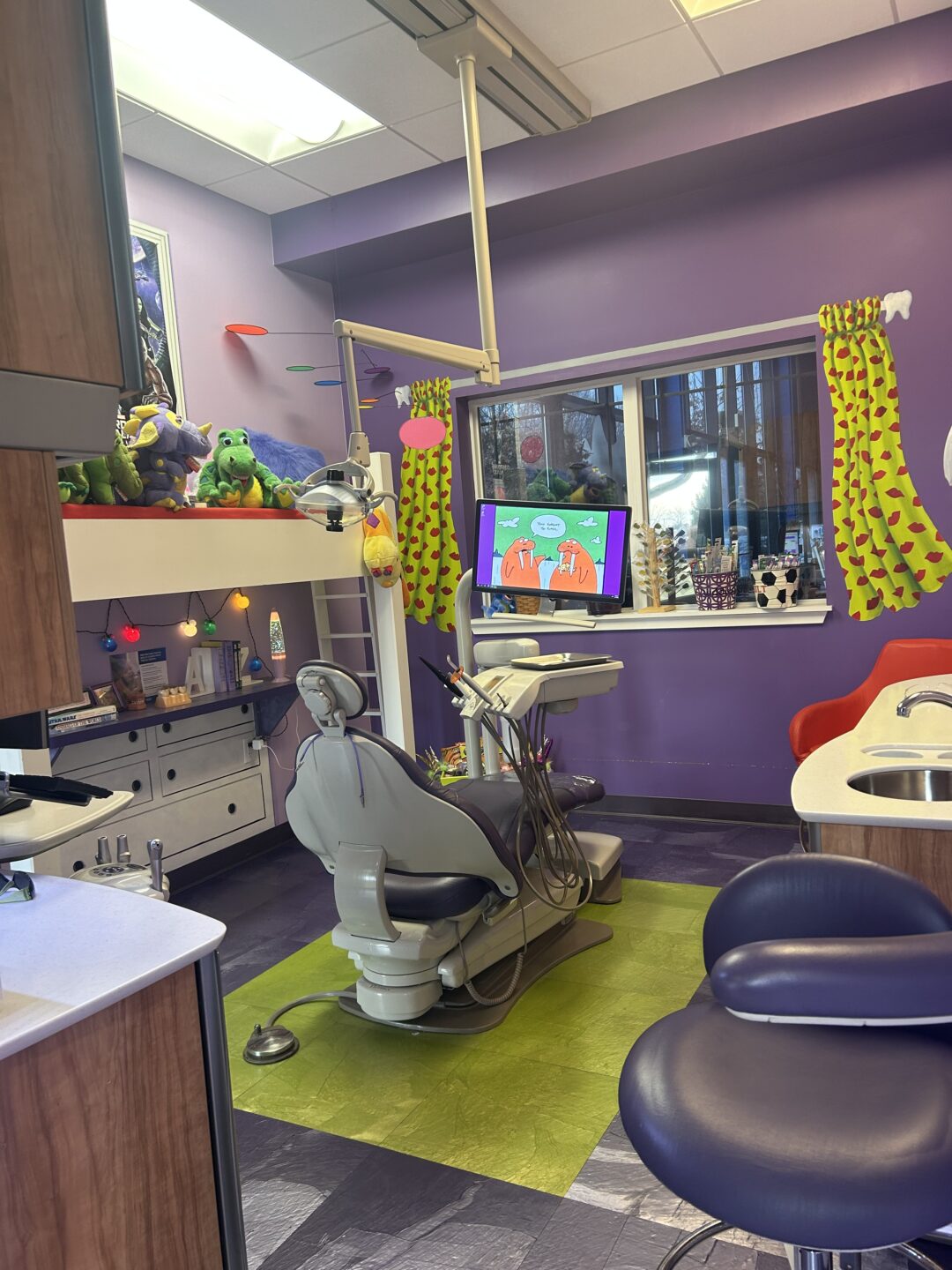  Image of kids’ dental exam room with puppets and a large-screen TV. 