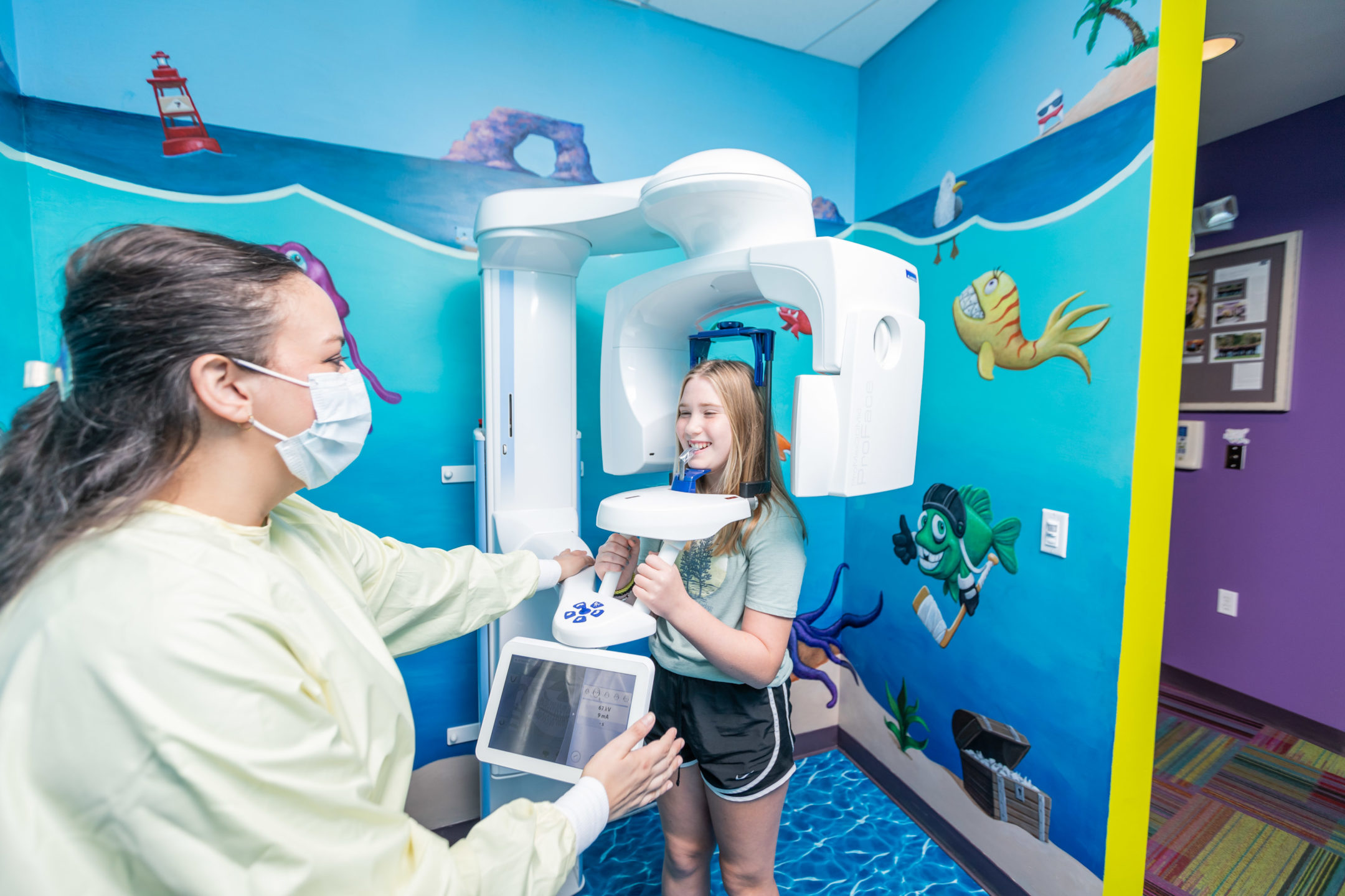 Young girl receives 3D x-ray imaging in fun, decorated room while technician provides instructions