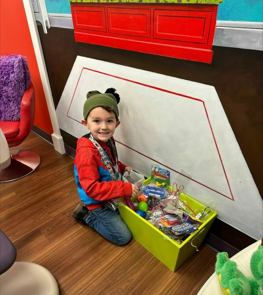 Image of smiling young boy at Newtown Dentistry for Kids picking out a toy after his dentist visit.