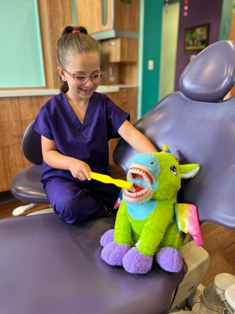  Image of excited young patient practicing her brushing skills with a stuffed animal.