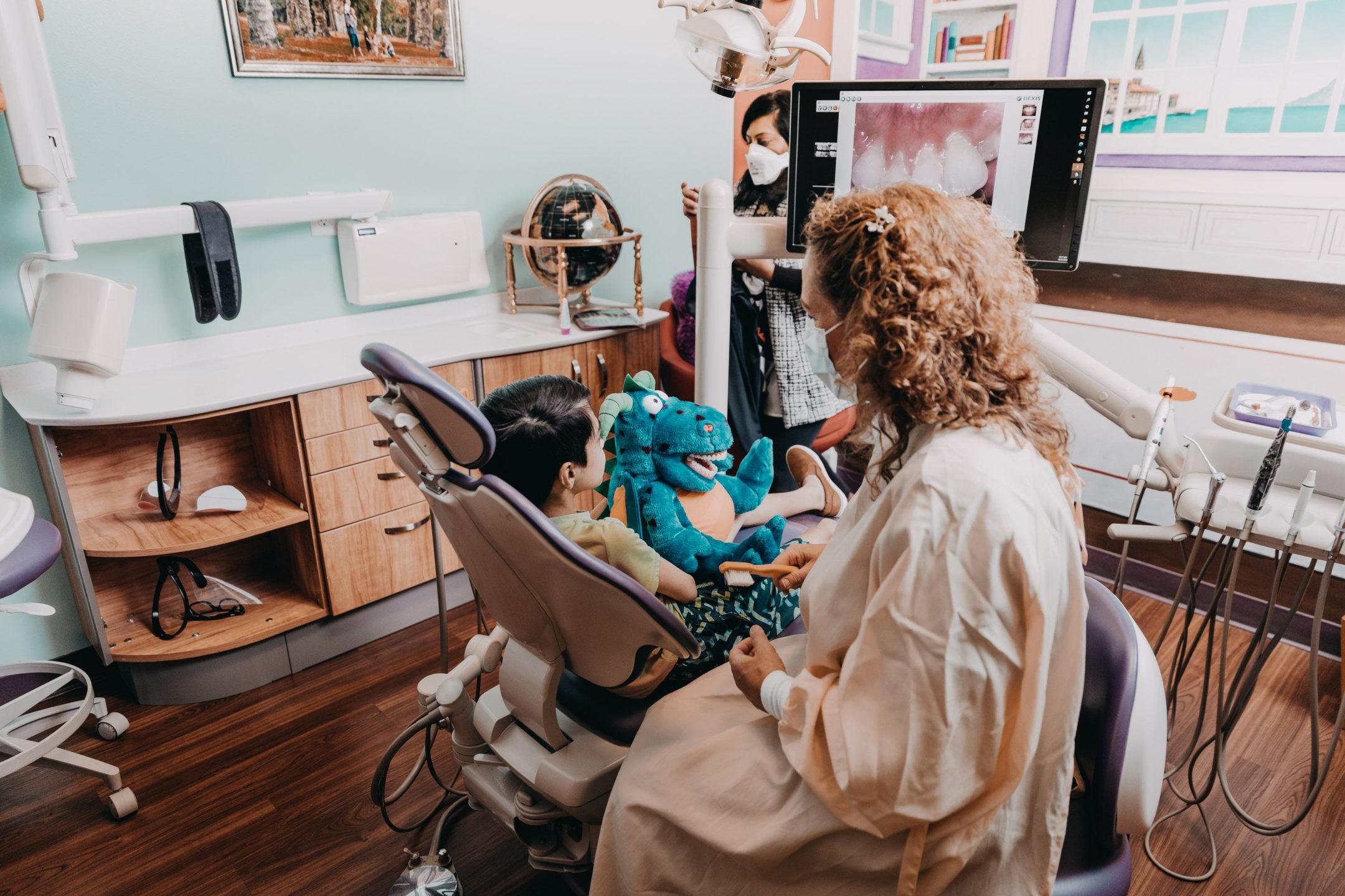  Young boy gets comfortable in the dentist chair while holding a friendly puppet. 