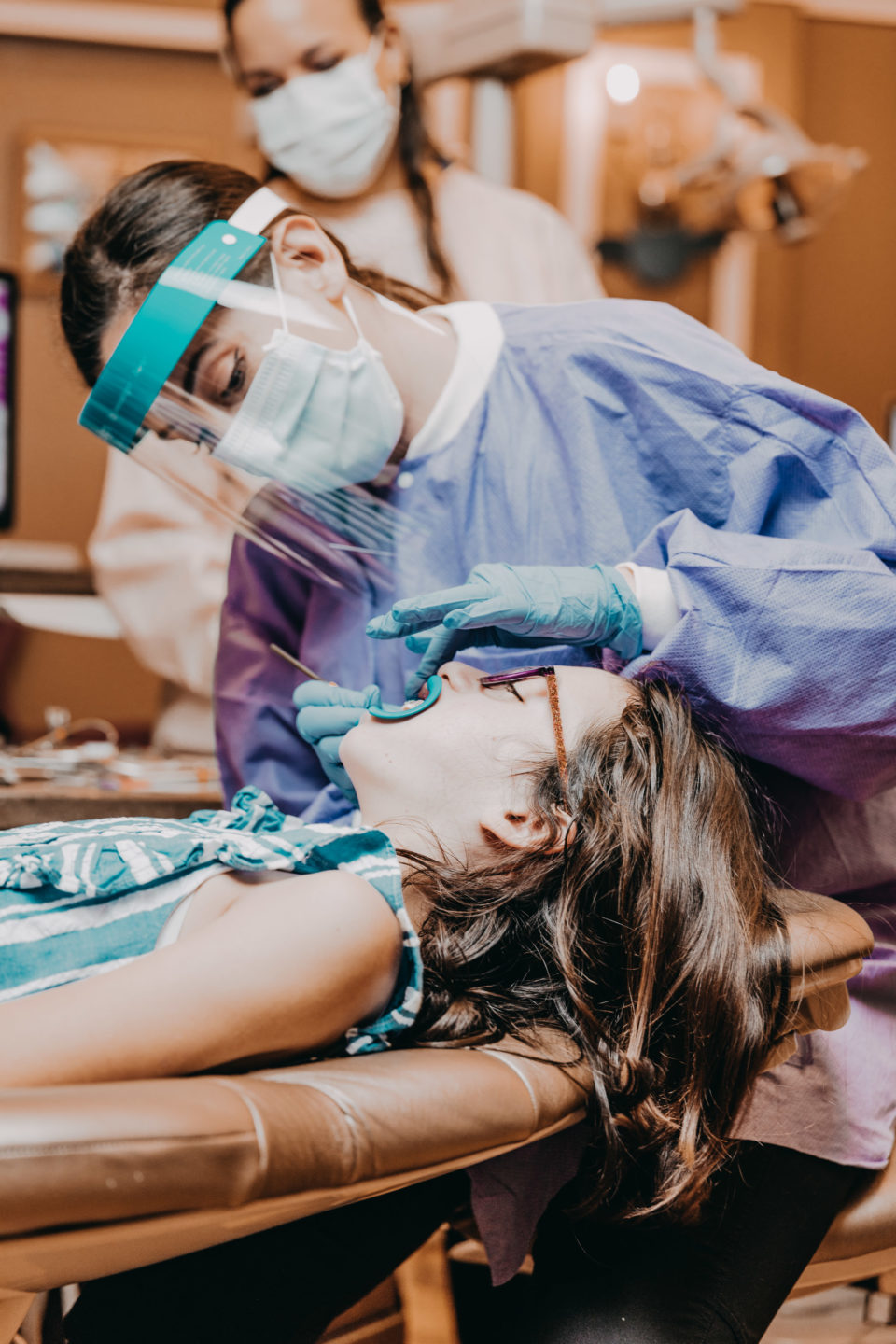 An orthodontist adjusts a young patient’s dental expander during an office visit.
