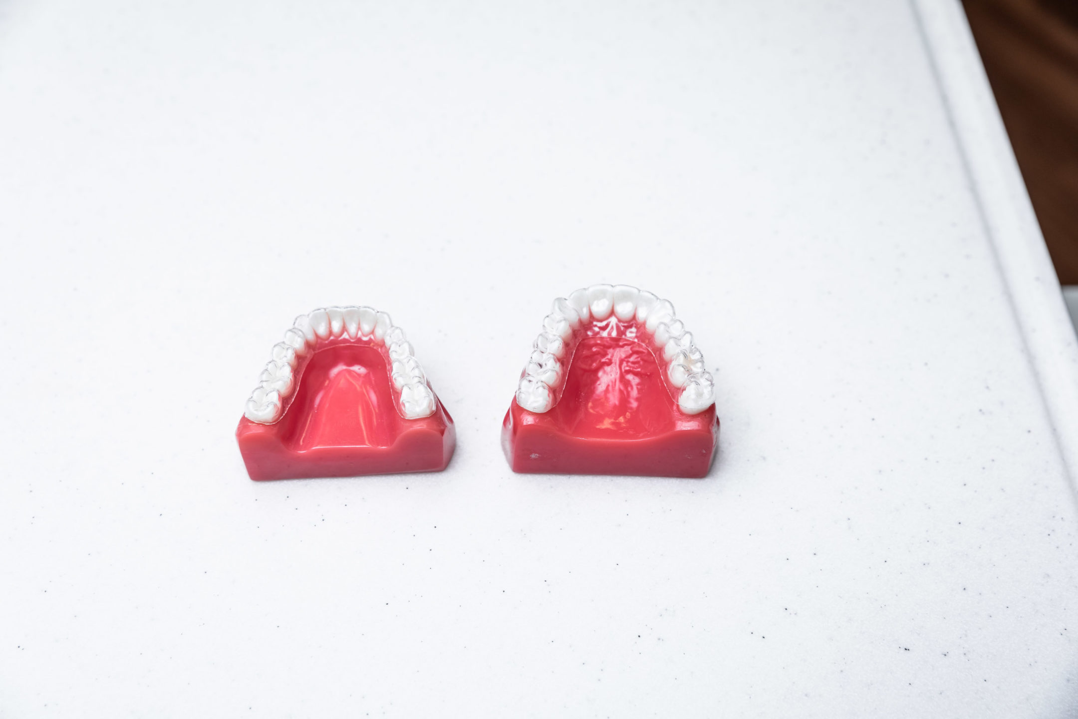  A model of clear aligners on teeth against a white background. 
