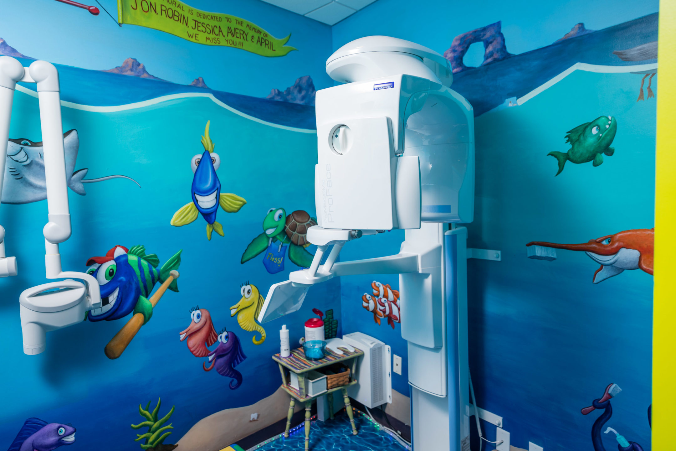  A dental exam room is brightly colored and decorated with fish in an underwater scene. 