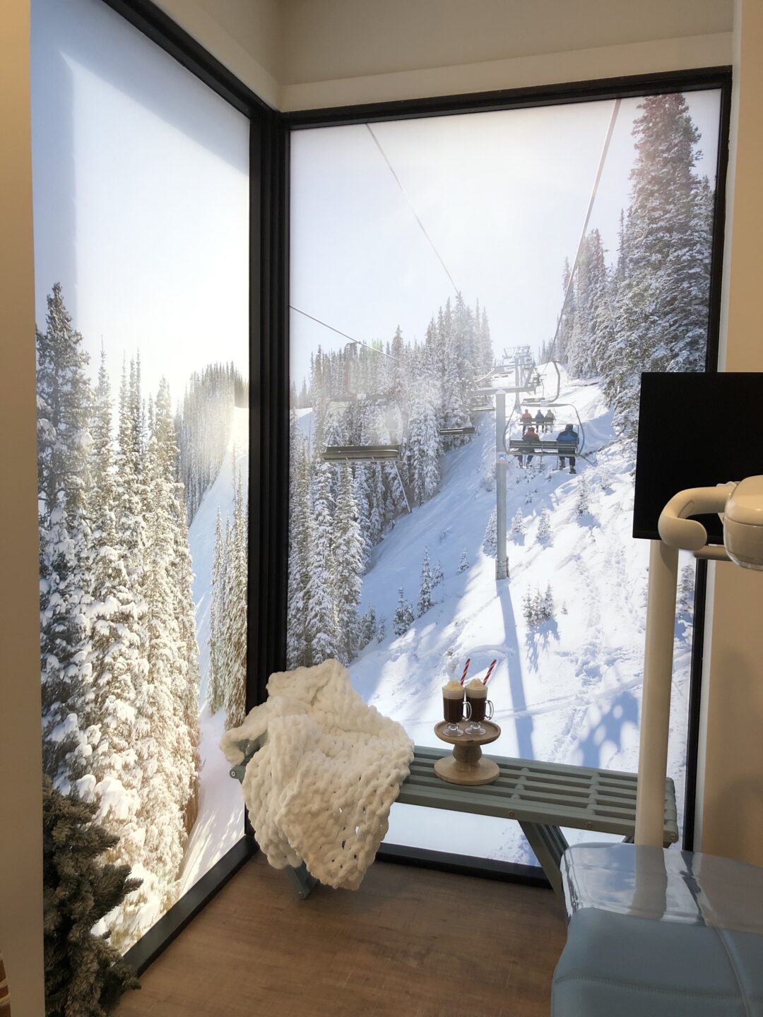 The inside of a dental exam room mimics a ski lodge with mountain scenes, a bench, and hot chocolate.