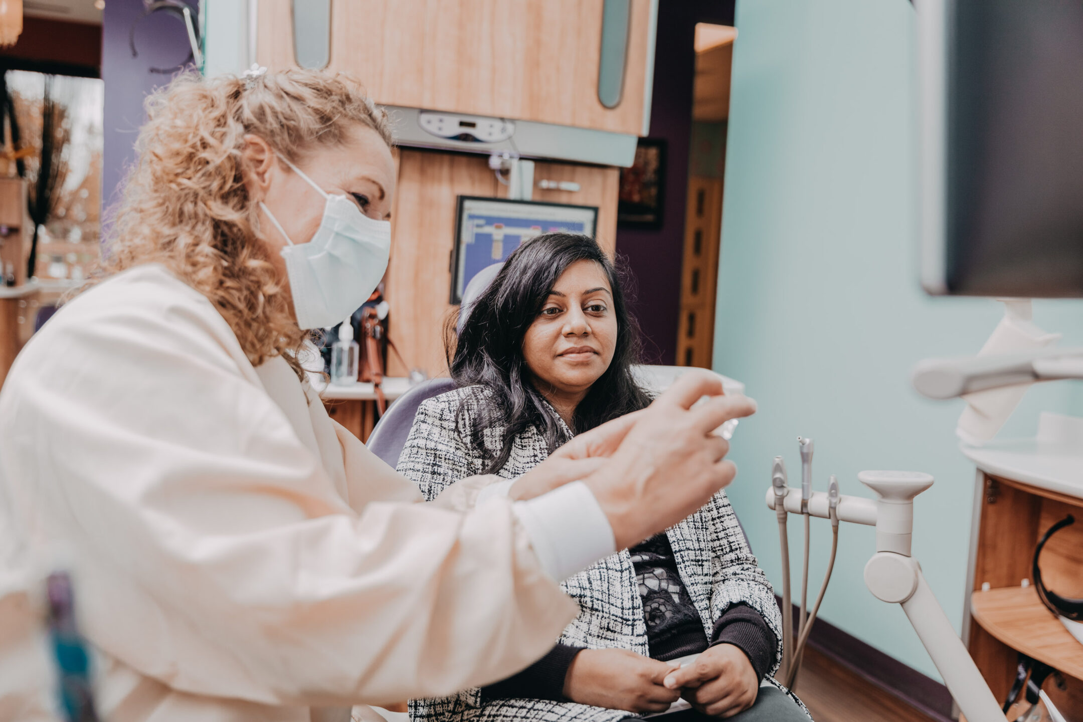  Image of female dentist showing dental mold to female patient in dentist office. 