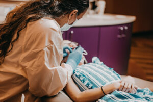 A dental professional works on a girl in a dental chair.