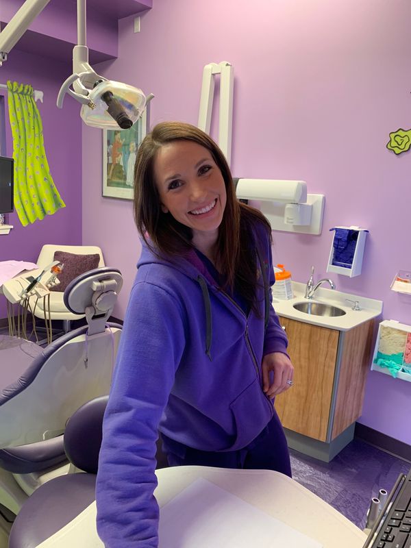A team member in a dental office smiles for the camera in an exam room.