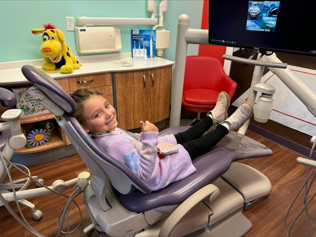 A young patient smiling in a dental chair.
