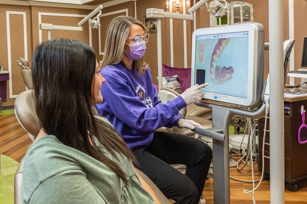 Image of orthodontist showing how braces work to an adult female patient.